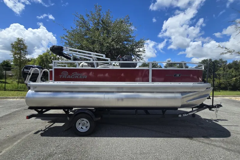 The Image of 2026 Sun Tracker Bass Buggy 18 DLX pontoon boat on trailer, parked outdoors. - 0