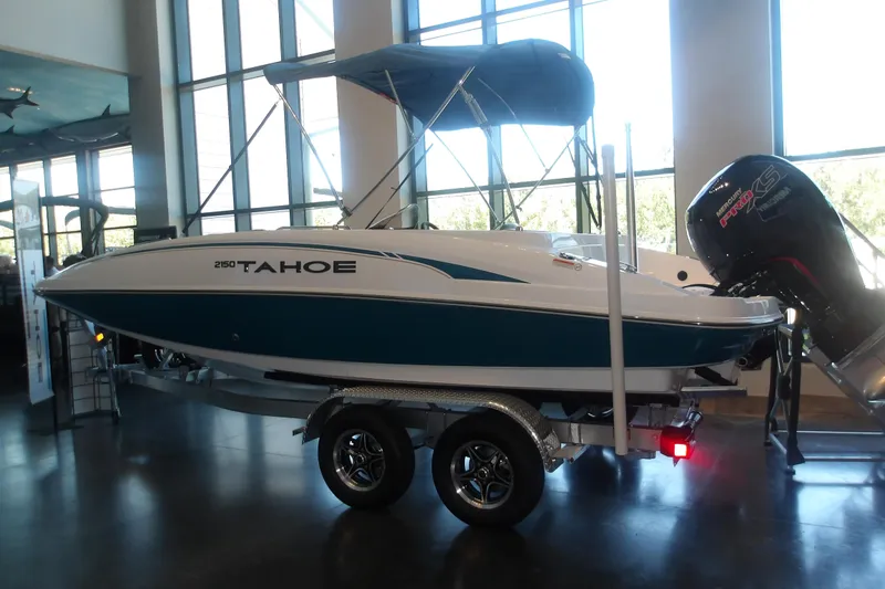 Slide: The Image of 2026 Tahoe 2150 boat displayed indoors with a powerful outboard motor. - 2