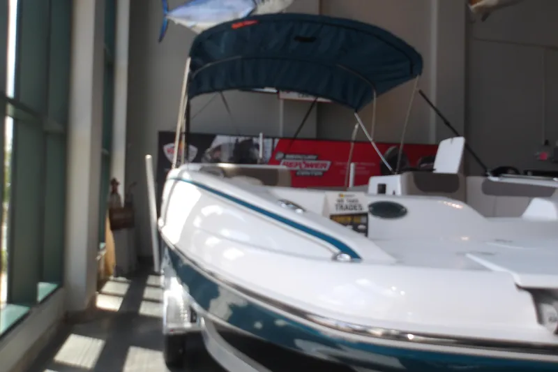 Slide: The Image of 2026 Tahoe 2150 boat with canopy displayed indoors, showcasing sleek design and modern features. - 4