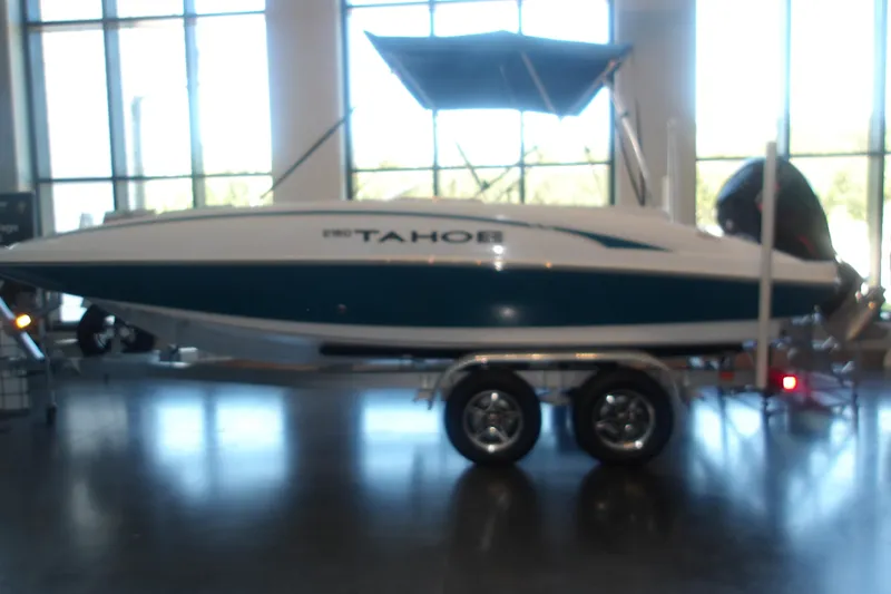 The Image of 2026 Tahoe 2150 boat on trailer in showroom with large windows. - 0