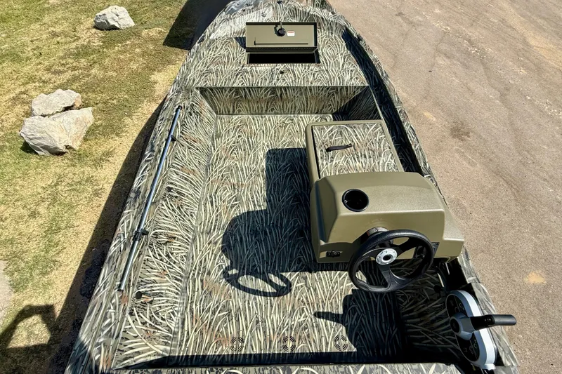 Slide: The Image of 2026 Tracker Grizzly 1648 SC boat with camouflage interior, steering console, and storage compartment. - 16
