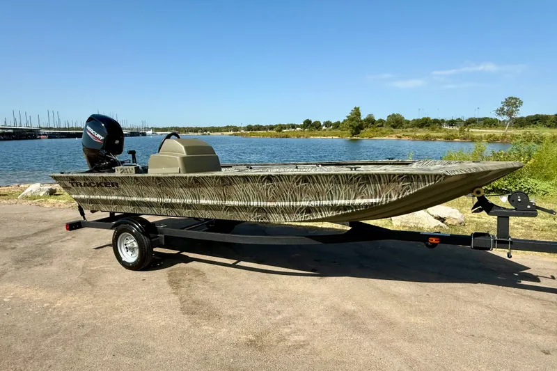 The Image of 2026 Tracker Grizzly 1648 SC boat on trailer by a scenic lake. - 0