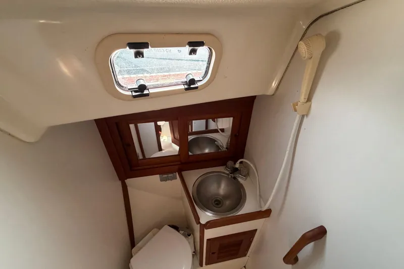 Slide: The Image of Compact bathroom in 1991 Tartan 28 Piper sailboat with sink, mirror, and porthole window. - 21