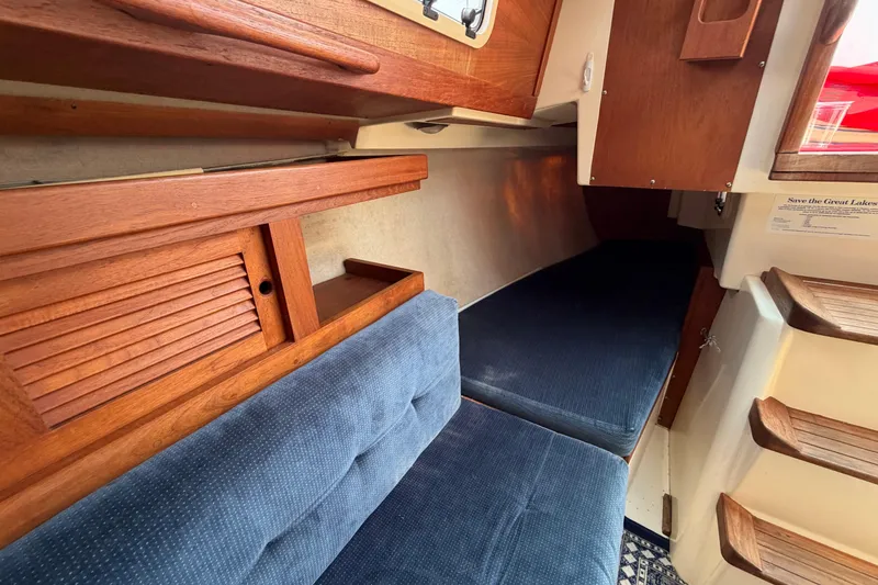 Slide: The Image of Interior of 1991 Tartan 28 Piper sailboat with wooden cabinetry and blue upholstery. - 18