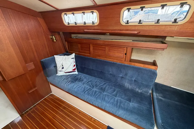 Slide: The Image of Interior of 1991 Tartan 28 Piper sailboat with blue cushioned seating and wooden accents. - 17