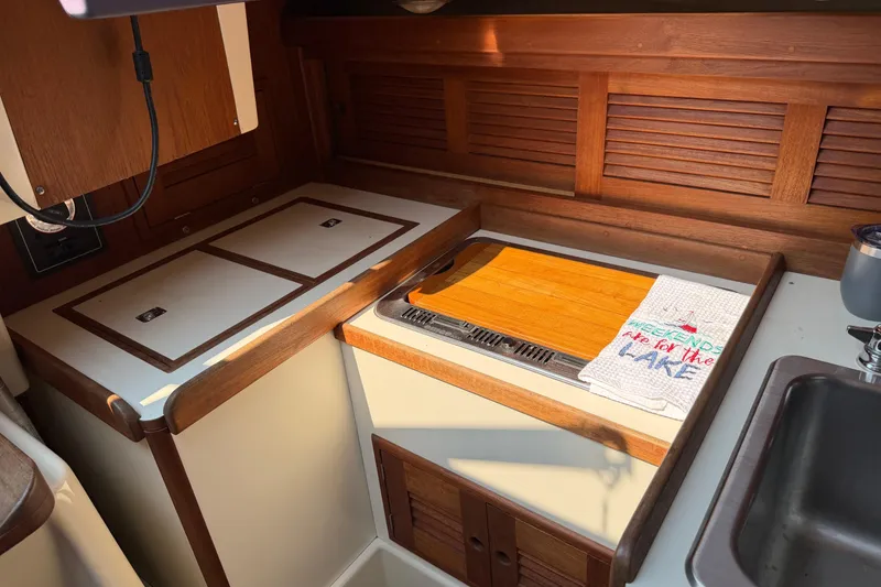 Slide: The Image of 1991 Tartan 28 Piper yacht interior kitchen with wooden cabinetry and countertop. - 11
