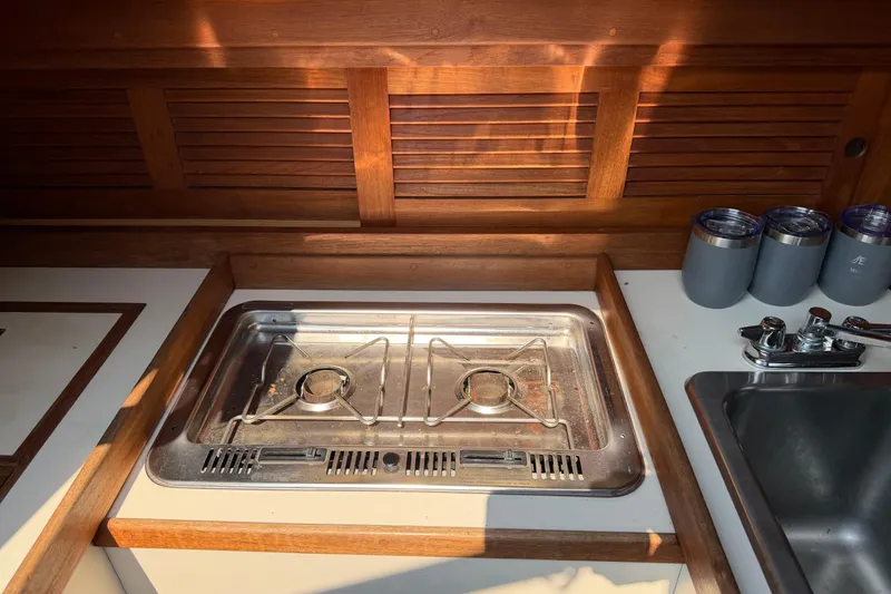 Slide: The Image of Compact kitchen area in a 1991 Tartan 28 Piper sailboat, featuring a stove and sink. - 12