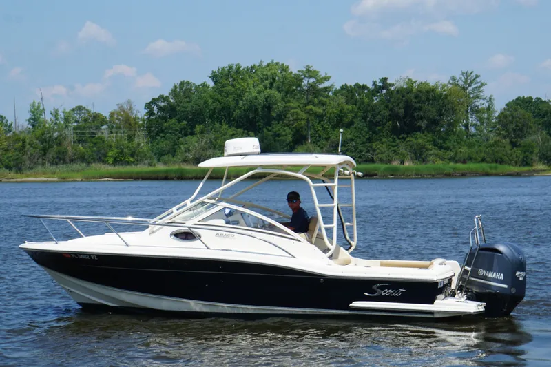 Slide: The Image of 2011 Scout 225 Abaco boat cruising on a calm river with lush green trees in the background. - 15