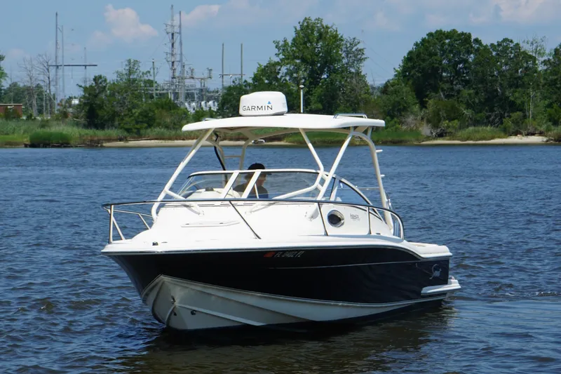Slide: The Image of 2011 Scout 225 Abaco boat on calm water with lush green shoreline. - 2
