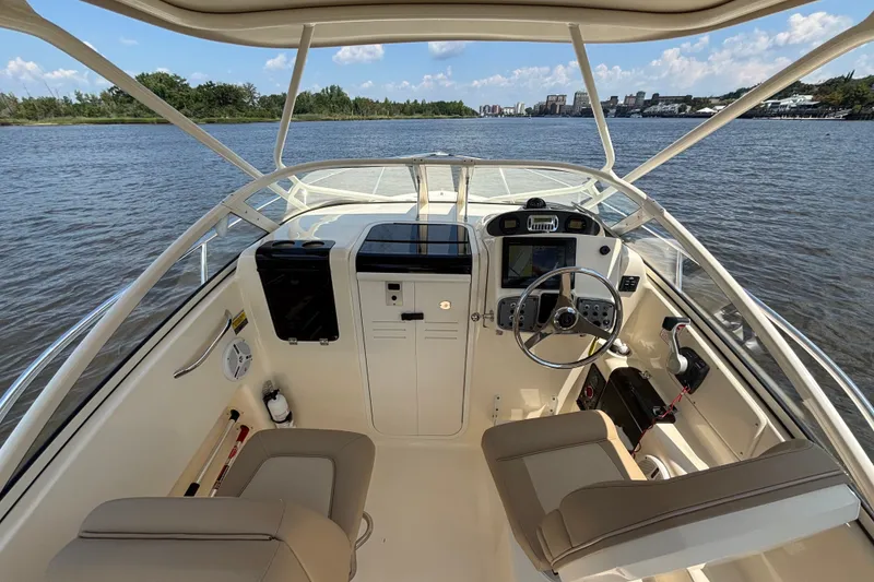 Slide: The Image of 2011 Scout 225 Abaco boat interior with steering wheel and navigation controls on a sunny day. - 6