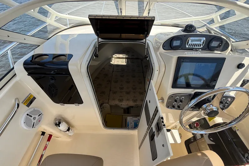 Slide: The Image of 2011 Scout 225 Abaco boat cockpit with steering wheel, control panel, and cabin entrance. - 10