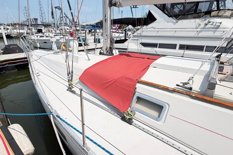 Slide: The Image of 1988 Beneteau Oceanis 390 sailboat docked at marina, featuring red deck cover. - 6