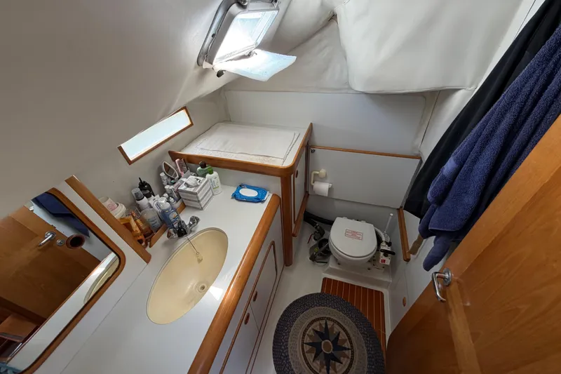 Slide: The Image of Bathroom interior of 1988 Beneteau Oceanis 390 yacht, featuring sink, toilet, and storage. - 21