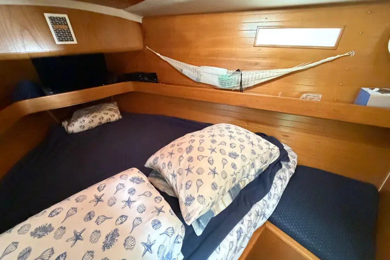 Slide: The Image of Cozy cabin interior of 1988 Beneteau Oceanis 390 sailboat with nautical-themed bedding. - 31