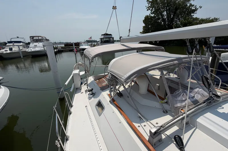 Slide: The Image of 1988 Beneteau Oceanis 390 sailboat docked at marina, featuring dual canopies and rigging. - 16