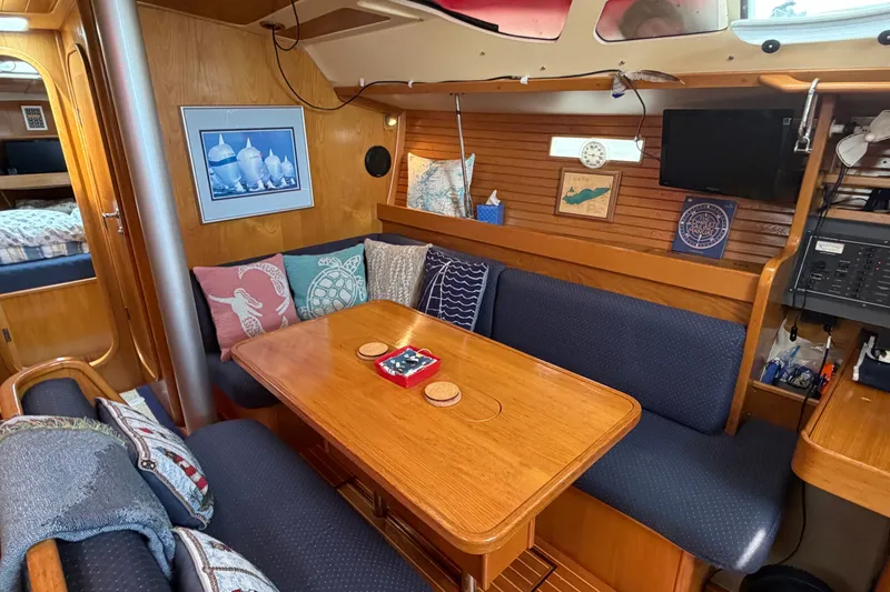 Slide: The Image of Cozy interior of 1988 Beneteau Oceanis 390 sailboat with wooden dining area and nautical decor. - 17