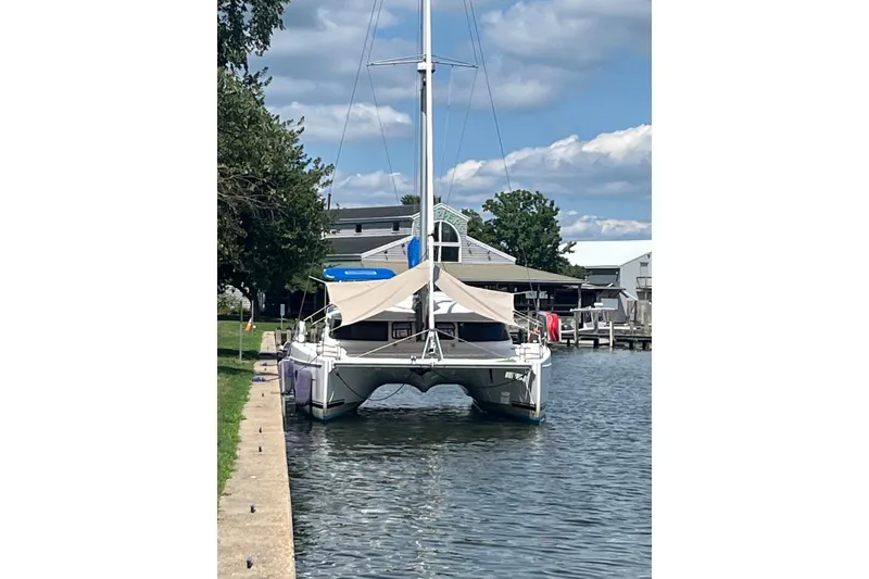 Slide: The Image of 2013 Fountaine Pajot Lipari 41 catamaran docked by a waterfront house. - 1
