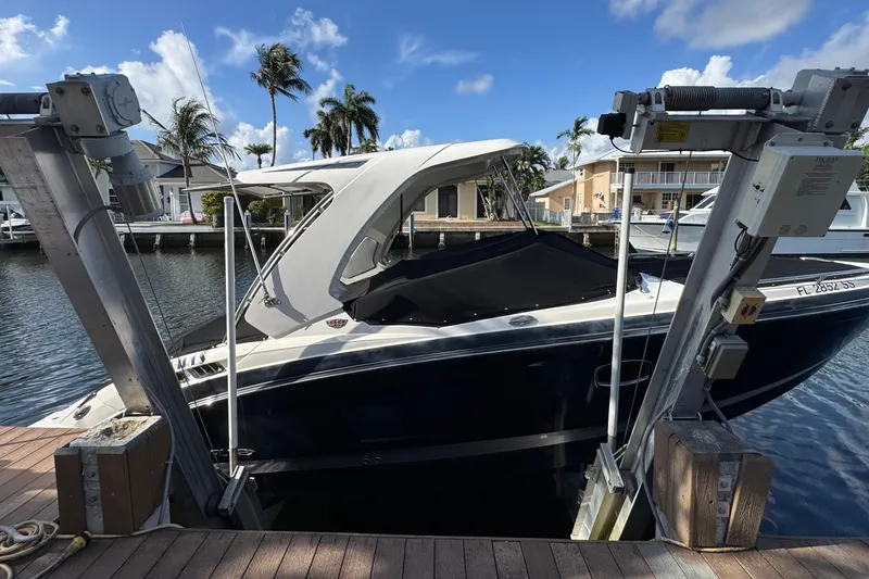 Slide: The Image of 2019 Chaparral 317 SSX boat docked, covered, with palm trees and waterfront homes in the background. - 4