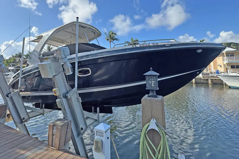 Slide: The Image of 2019 Chaparral 317 SSX boat on lift by waterfront dock, under clear blue sky. - 2