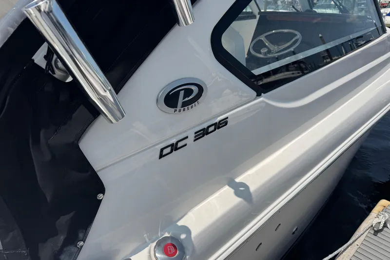 Slide: The Image of 2025 Pursuit DC 306 Dual Console boat docked, showcasing sleek design and branding. - 8