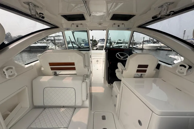Slide: The Image of Interior of 2025 Pursuit DC 306 Dual Console boat, featuring sleek seating and helm. - 11