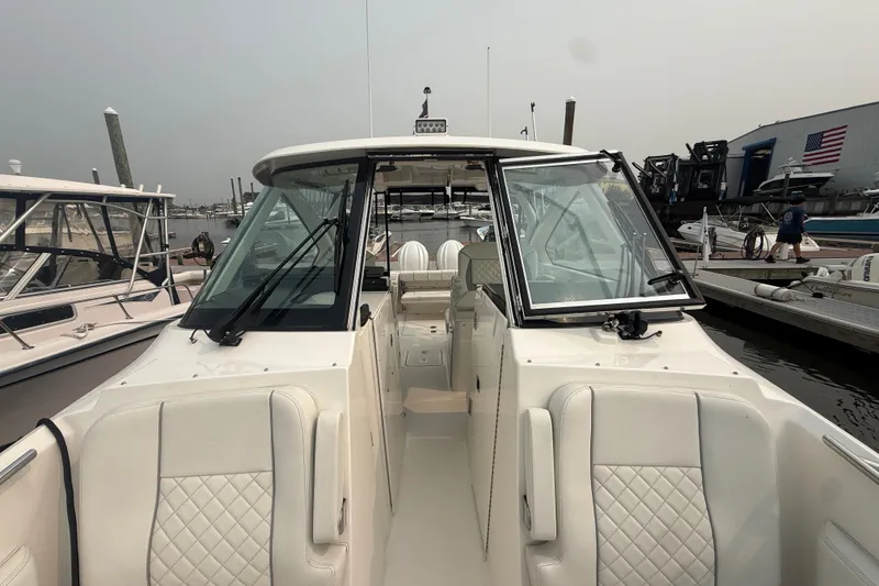 Slide: The Image of 2025 Pursuit DC 306 Dual Console boat docked at marina, showcasing sleek design and spacious interior. - 32