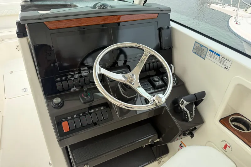 Slide: The Image of Helm of 2025 Pursuit DC 306 Dual Console with modern controls and steering wheel. - 25