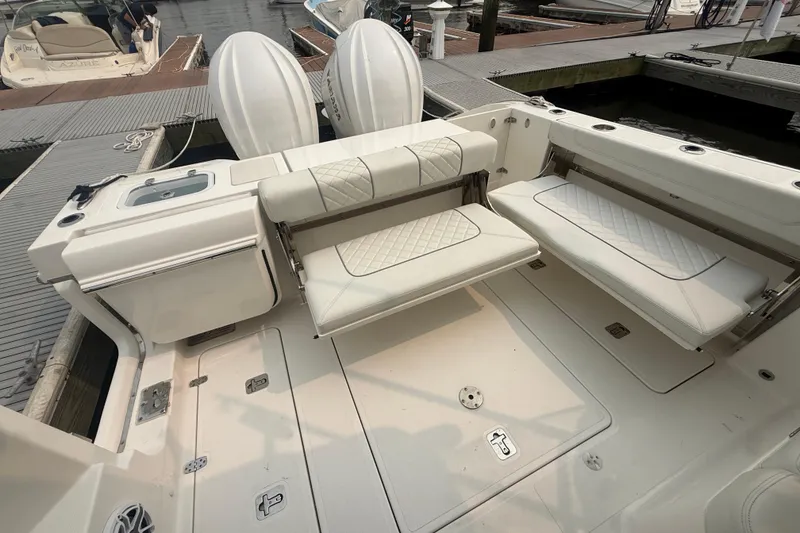Slide: The Image of 2025 Pursuit DC 306 Dual Console boat interior with white seating and deck at marina. - 10