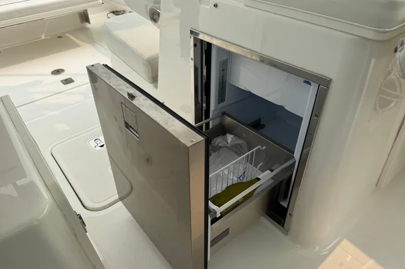 Slide: The Image of Open refrigerator on 2025 Pursuit DC 306 Dual Console boat, showcasing interior storage. - 15