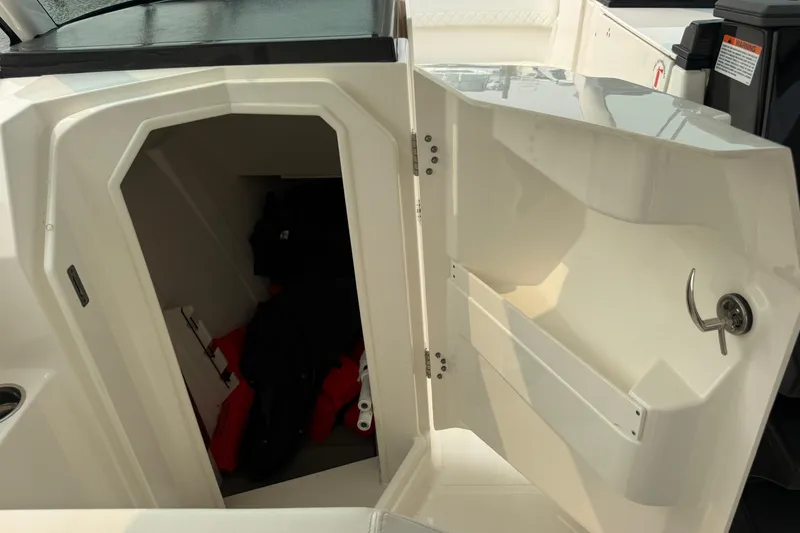 Slide: The Image of 2025 Pursuit DC 306 Dual Console boat storage compartment with open door. - 21