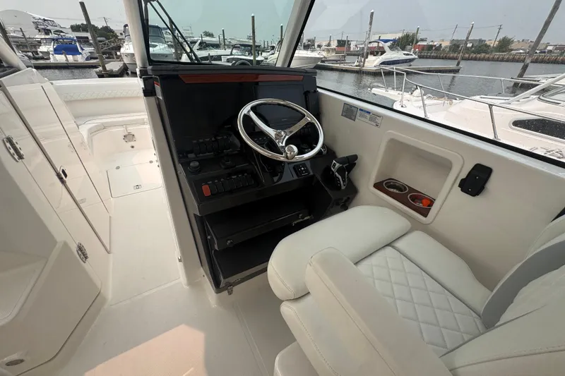 Slide: The Image of 2025 Pursuit DC 306 Dual Console boat interior with steering wheel and seating. - 23