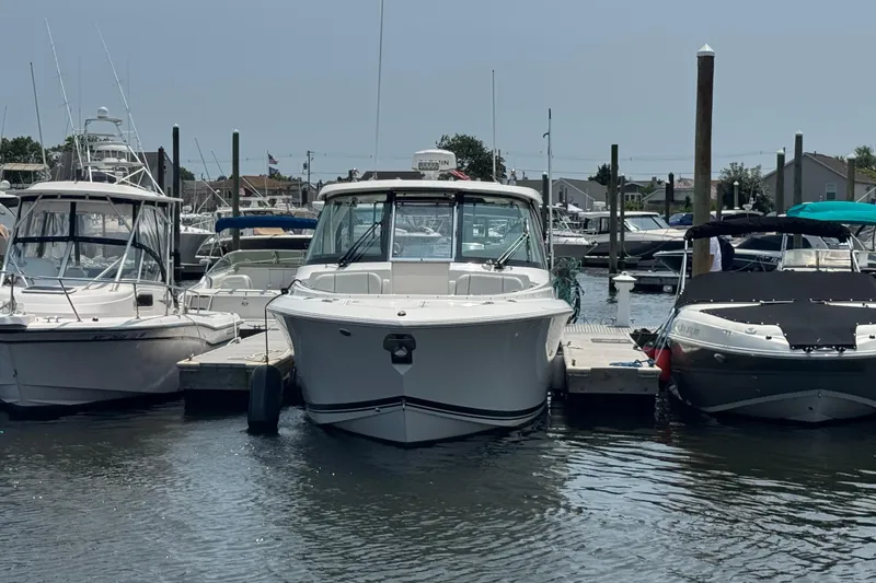 Slide: The Image of 2025 Pursuit DC 306 Dual Console boat docked at a marina, surrounded by other vessels. - 2