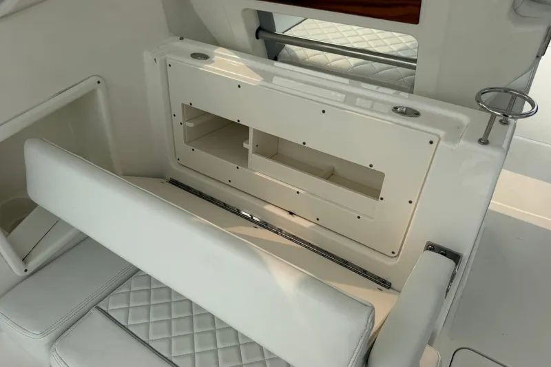 Slide: The Image of 2025 Pursuit DC 306 Dual Console interior with white seating and storage compartment. - 17