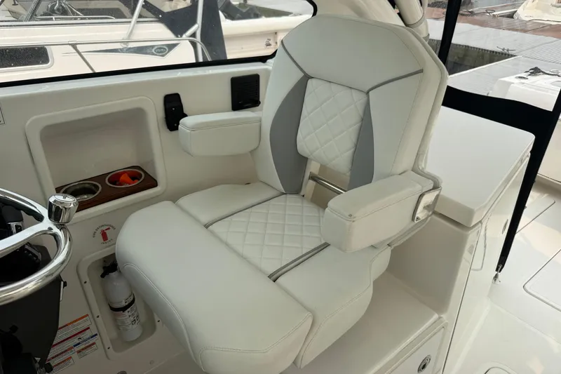 Slide: The Image of Luxurious helm seat on 2025 Pursuit DC 306 Dual Console boat, featuring elegant white upholstery. - 24