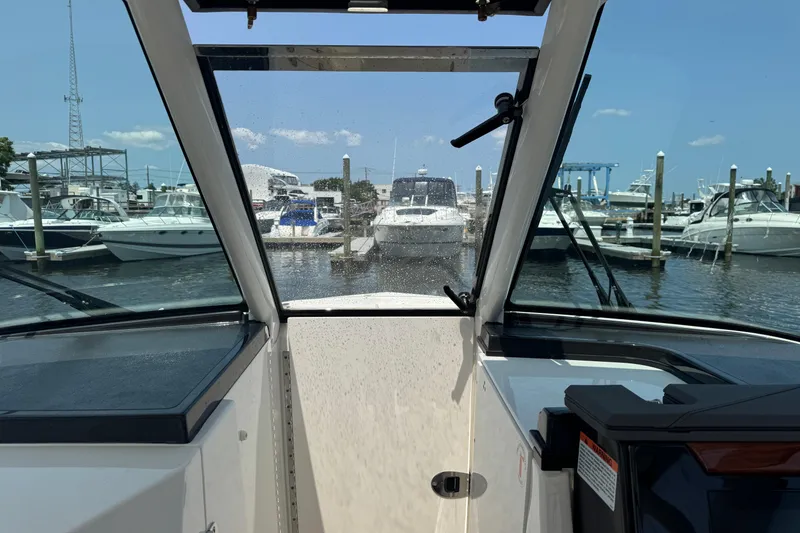 Slide: The Image of 2025 Pursuit DC 306 Dual Console boat docked at a marina, surrounded by other vessels. - 27