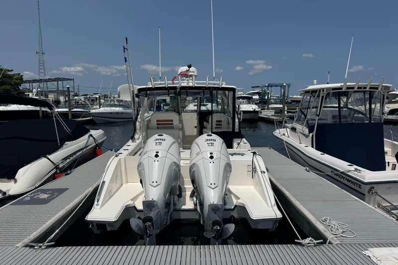 Slide: The Image of 2025 Pursuit DC 306 Dual Console boat docked with twin engines, surrounded by other boats. - 4