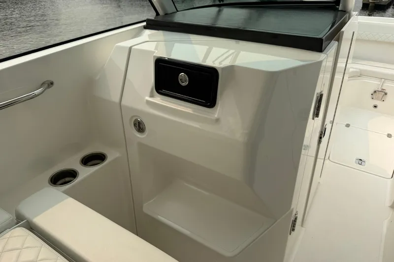 Slide: The Image of 2025 Pursuit DC 306 Dual Console interior with cup holders and storage compartment. - 20