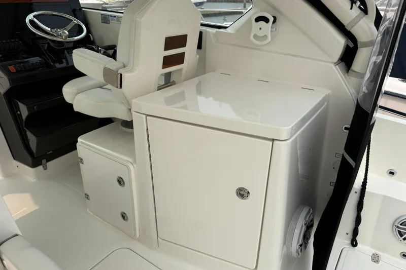 Slide: The Image of 2025 Pursuit DC 306 Dual Console interior with helm seat and storage compartments. - 13