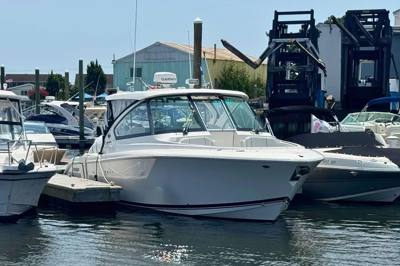 Slide: The Image of 2025 Pursuit DC 306 Dual Console boat docked at a marina. - 1