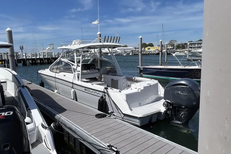 Slide: The Image of 2023 Solara S-250 DC boat docked at marina under clear blue sky. - 2