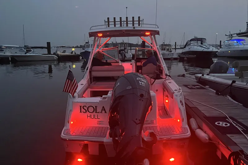 Slide: The Image of 2023 Solara S-250 DC boat docked at marina with red lights and American flag. - 7