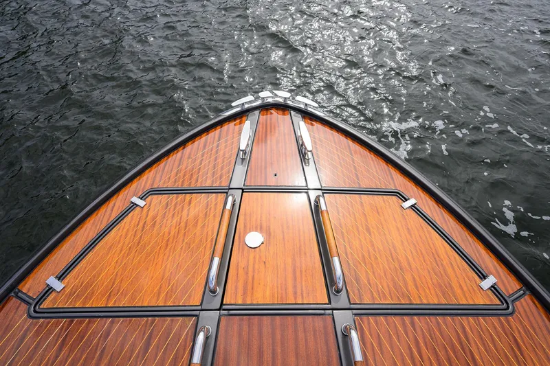 Slide: The Image of Bow of 2014 Riva 44' Rivarama yacht with polished wood deck on water. - 85