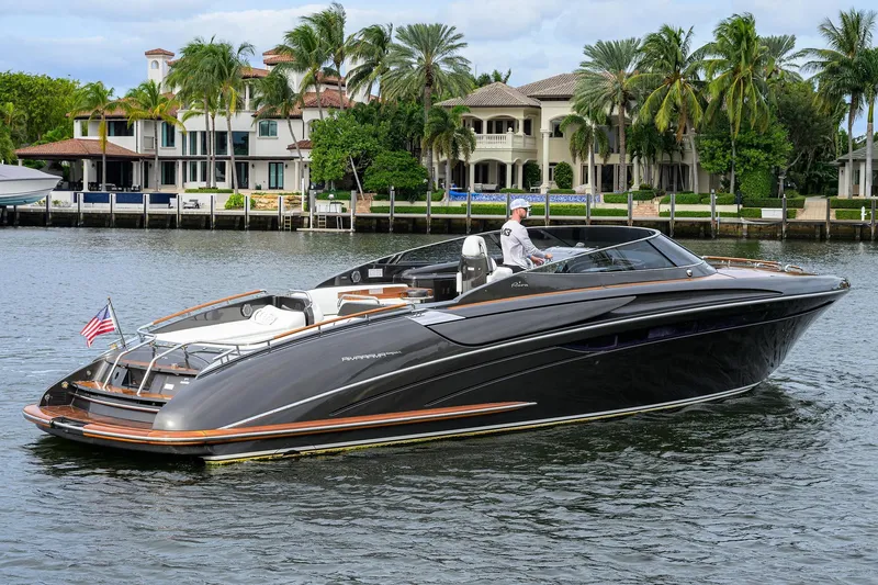 Slide: The Image of Luxurious 2014 Riva 44' Rivarama yacht cruising near waterfront homes, showcasing sleek design and elegance. - 2