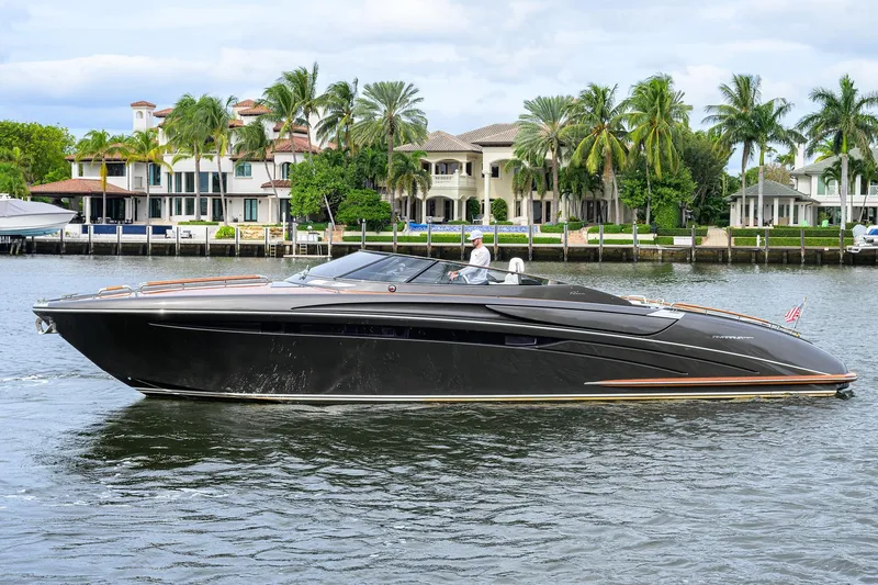Slide: The Image of Luxurious 2014 Riva 44' Rivarama yacht cruising near waterfront homes with palm trees. - 1