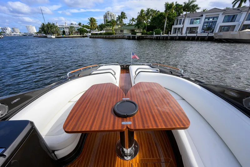 Slide: The Image of Luxurious 2014 Riva 44' Rivarama yacht with elegant seating and wooden table on a scenic waterway. - 52