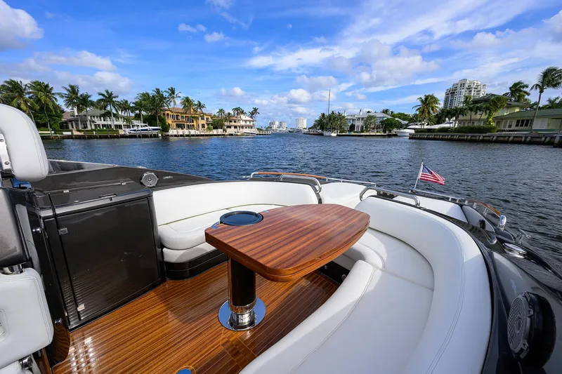 Slide: The Image of Luxurious 2014 Riva 44' Rivarama yacht with elegant seating and wooden table on a scenic waterway. - 54