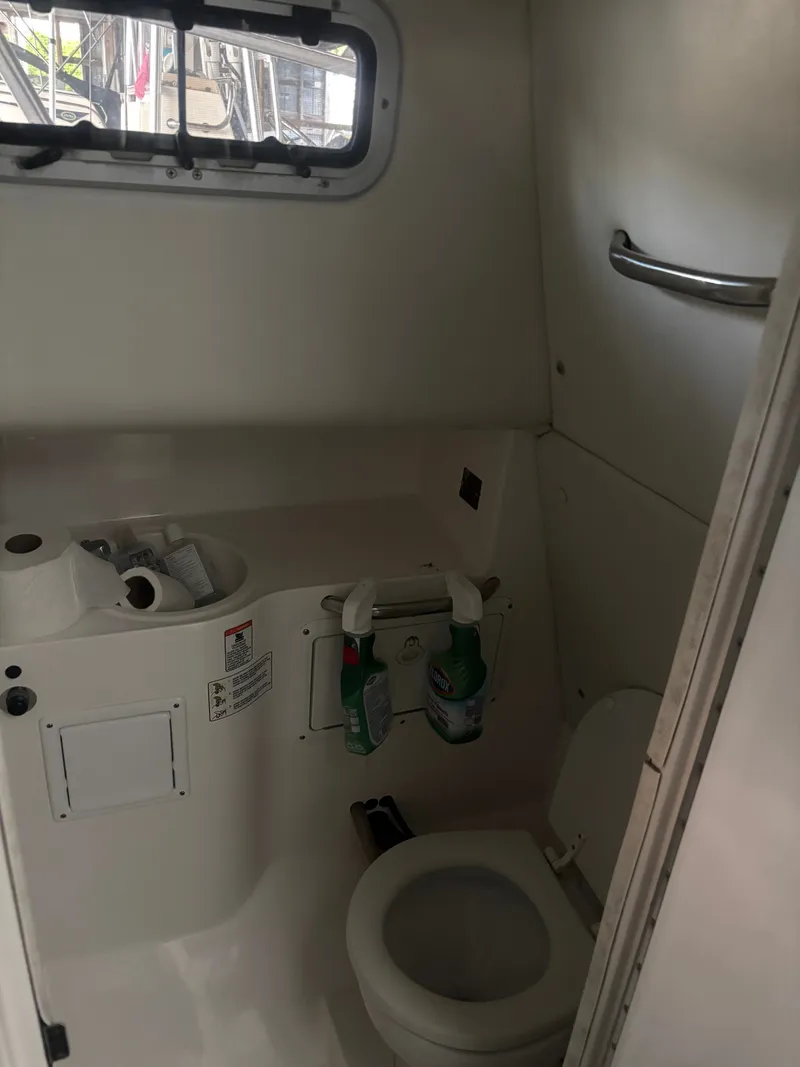 Slide: The Image of The image shows a compact boat toilet with a small sink and cleaning supplies. - 5