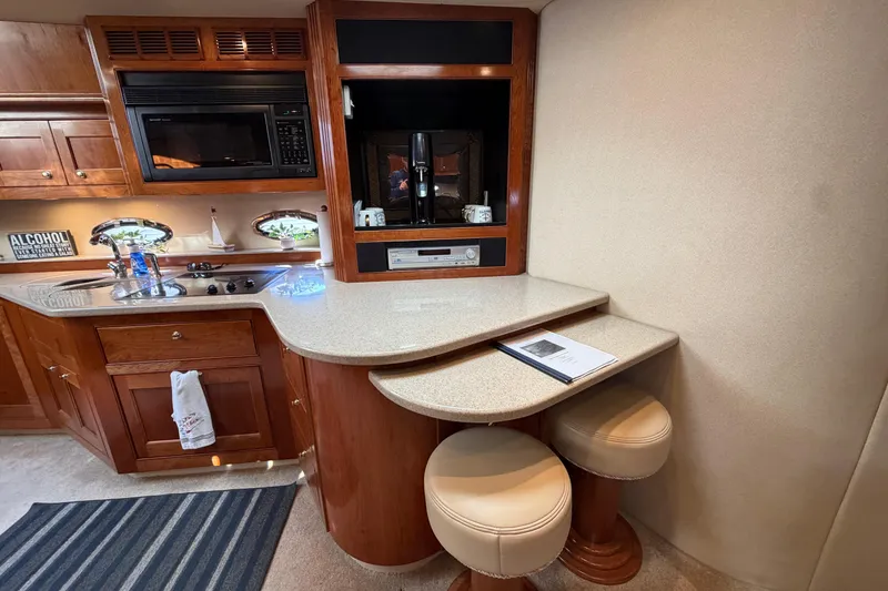 Slide: The Image of 2003 Cruisers Yachts 5470 Express interior with kitchenette, bar stools, and modern amenities. - 29