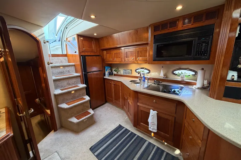 Slide: The Image of Luxurious 2003 Cruisers Yachts 5470 Express interior kitchen with wood cabinetry and modern appliances. - 27