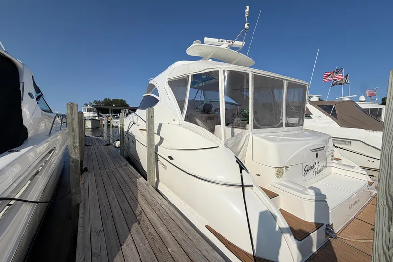 Slide: The Image of 2003 Cruisers Yachts 5470 Express docked at marina under clear blue sky. - 2